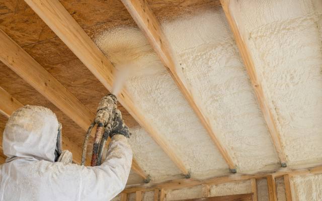 Spray foam insulation going onto the underside of a roof deck between the rafters