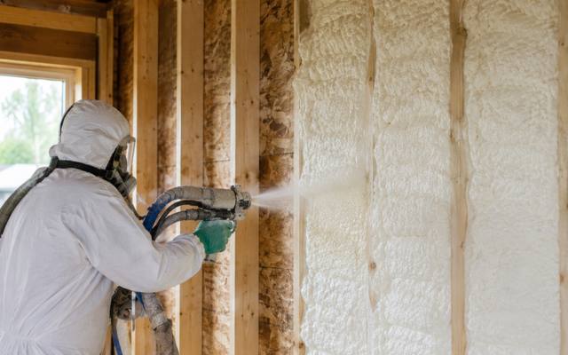 Installer spraying closed cell foam into a framed stud wall