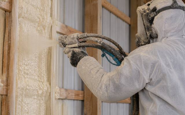 Spray foam insulation going in between the girts of a steel-clad shop wall